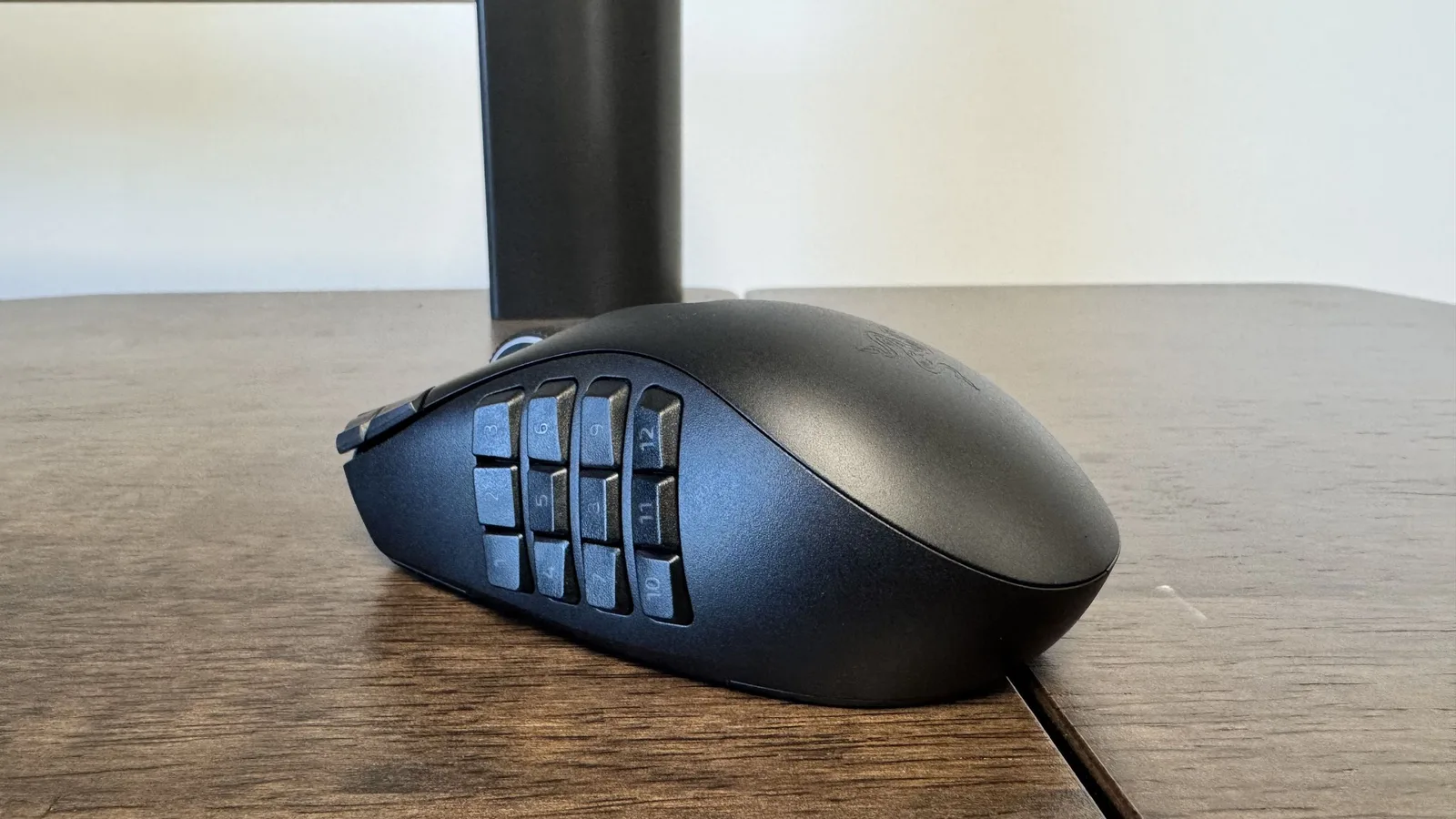 The Razer Naga V3 Pro on a wooden table from the back left