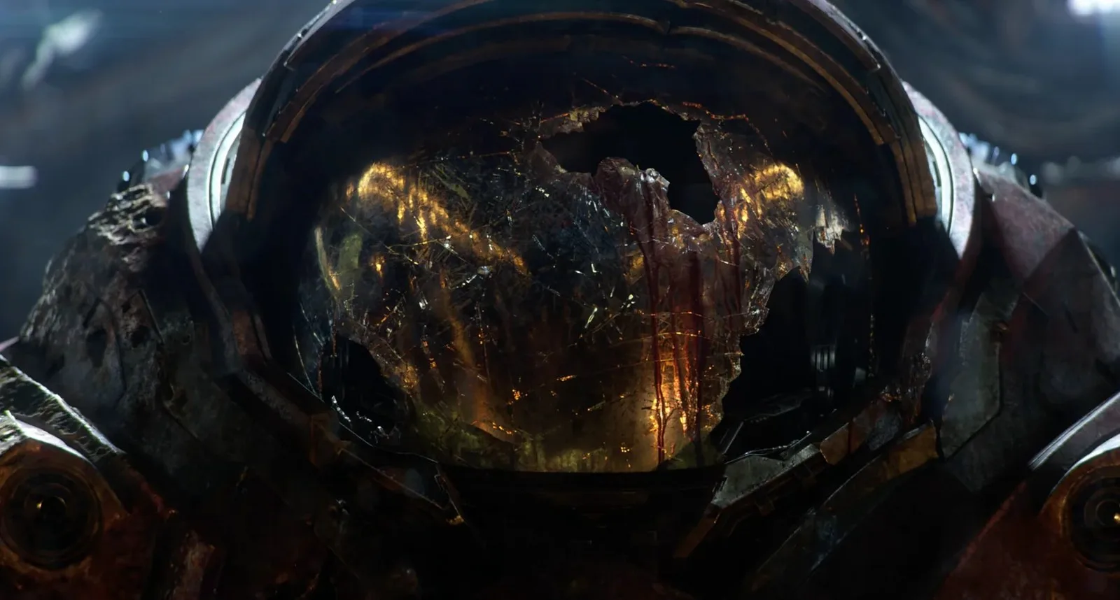Close-up of a damaged metallic suit of armor with a shattered, reflective helmet showing internal glowing lights and streaks of blood.