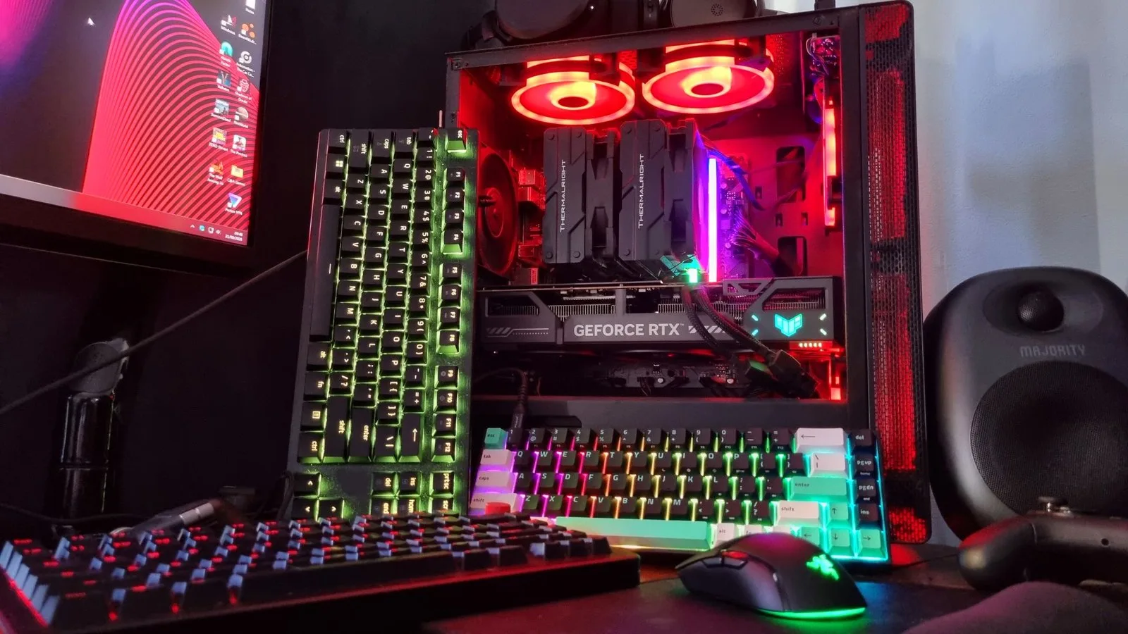 A collection of RGB-lit devices, including gaming keyboards and mice, next to an RGB-lit gaming PC