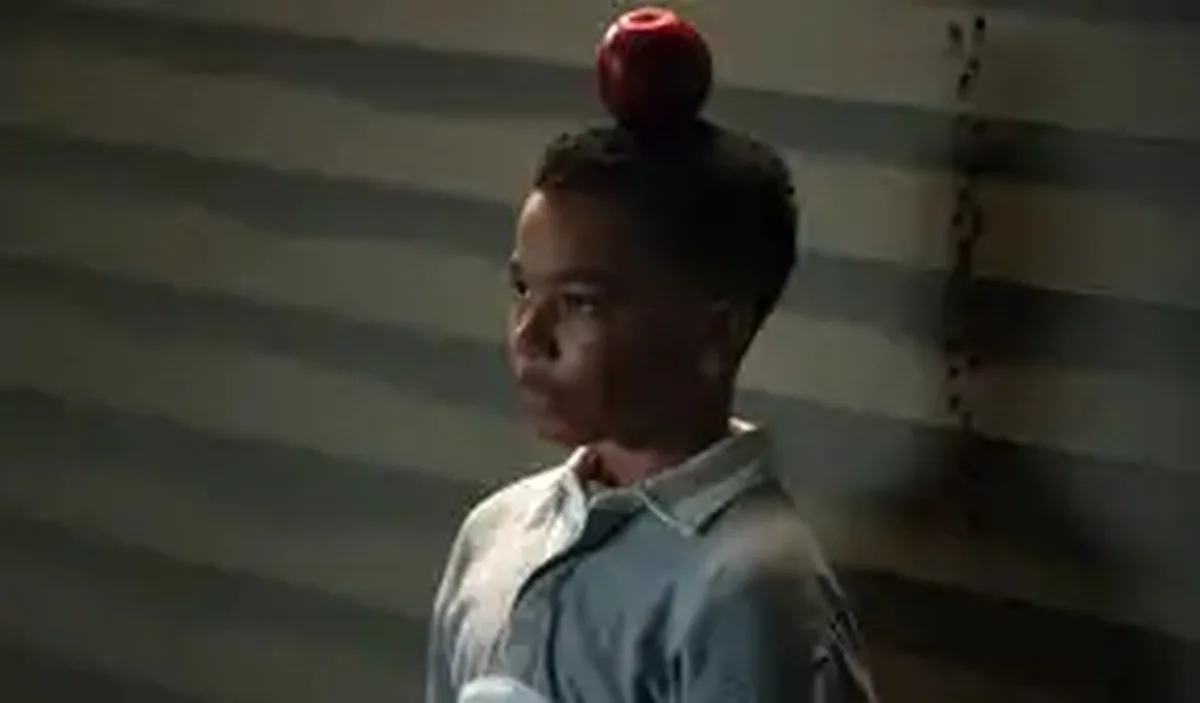 A young John Stewart (Cairo Cash Lee) stands with an apple balanced on his head in Lanterns