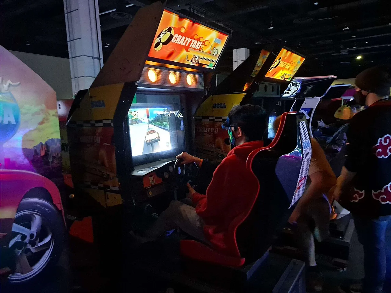 A man playing on a Crazy Taxi arcade cabinet at MAGFest 2023