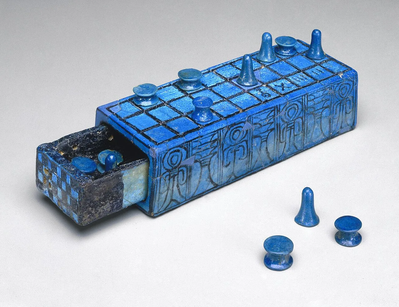 Ancient Egyptian senet game board inscribed for Amenhotep III with separate sliding drawer.  Created between 1390 and 1353 BC; made of glazed faience, dimensions: 5.5 × 7.7 × 21 cm. Held in the Brooklyn Museum, (New York City).